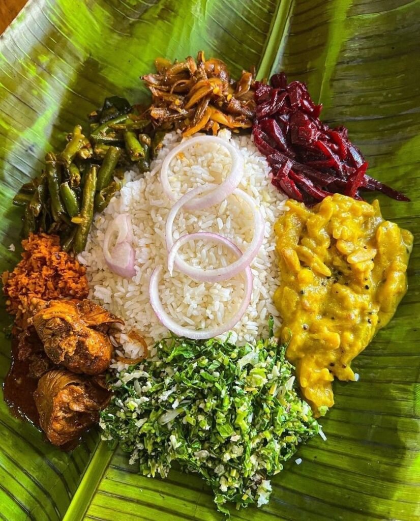 Traditional Sri Lankan rice and curry with chicken curry, mallung, sambol, and vegetable curries served on a banana leaf
