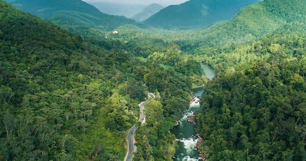 Aerial view of Kitulgala rainforest and Kelani River surrounded by lush tropical mountains in Sri Lanka.