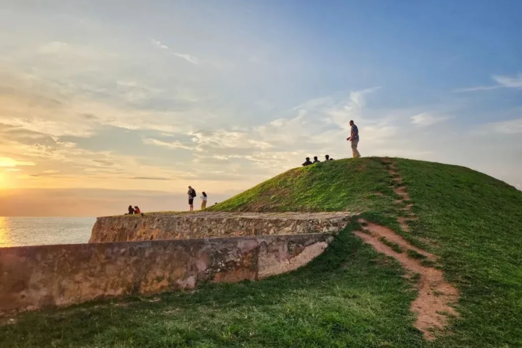 Visitors enjoying sunset views from the historic Galle Fort ramparts overlooking the Indian Ocean in Sri Lanka.