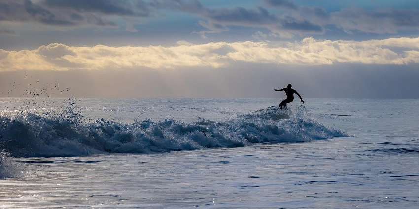 Surfer riding an ocean wave at Arugam Bay, one of Sri Lanka’s most famous surfing destinations.