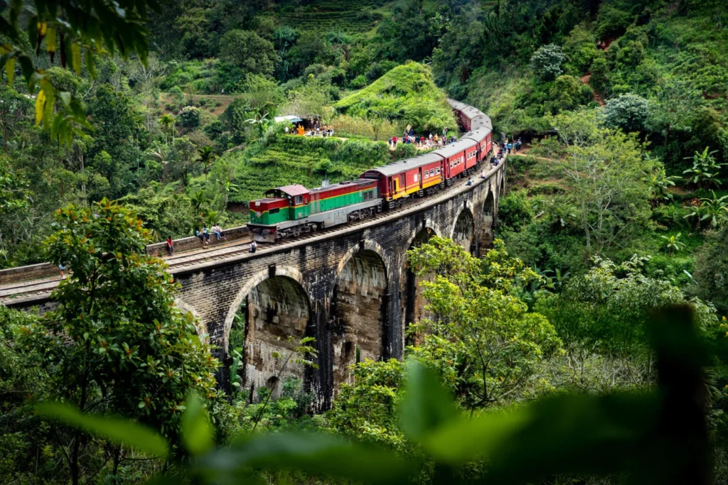 Scenic Sri Lankan train crossing the historic Nine Arch Bridge surrounded by lush green hills near Ella, Sri Lanka.