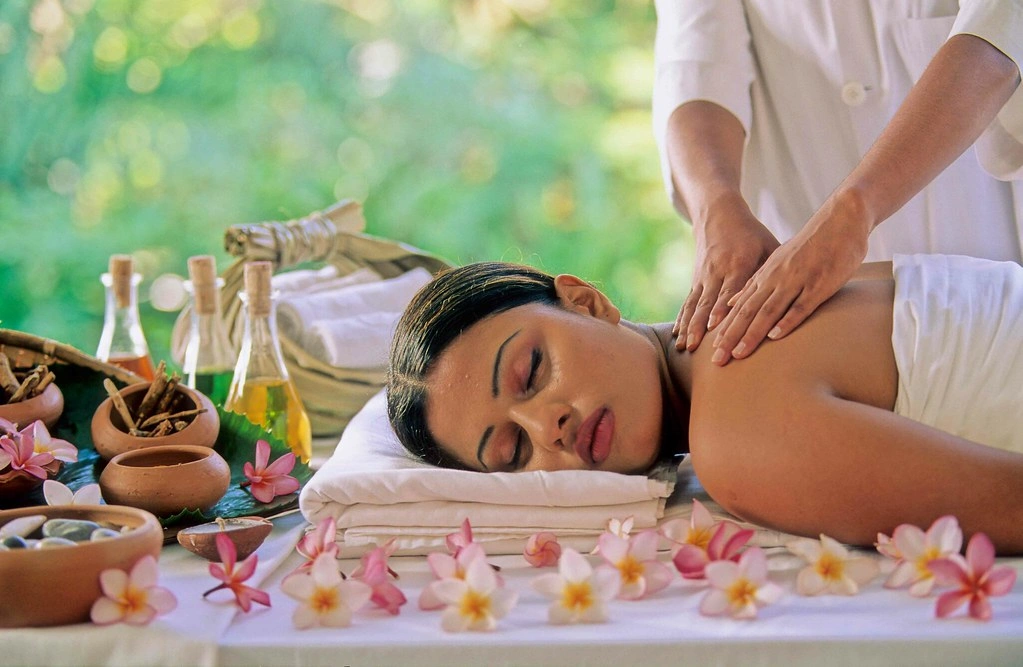 Woman receiving a relaxing Ayurvedic massage treatment with herbal oils in a peaceful tropical wellness setting in Sri Lanka.